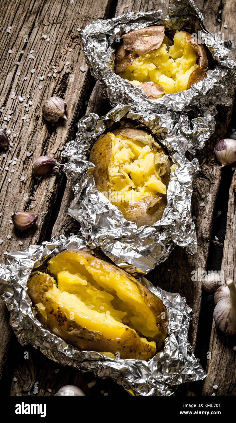Alimentos de patata . Las papas al horno en papel de aluminio sobre una  mesa de madera Fotografía de stock - Alamy