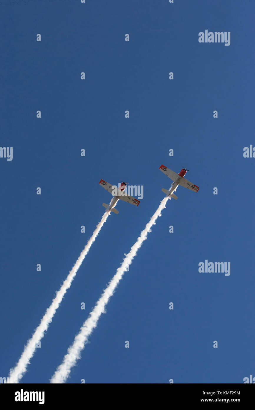Dos aviones de hélice volando junto con el rastro de humo en el cielo azul profundo Foto de stock