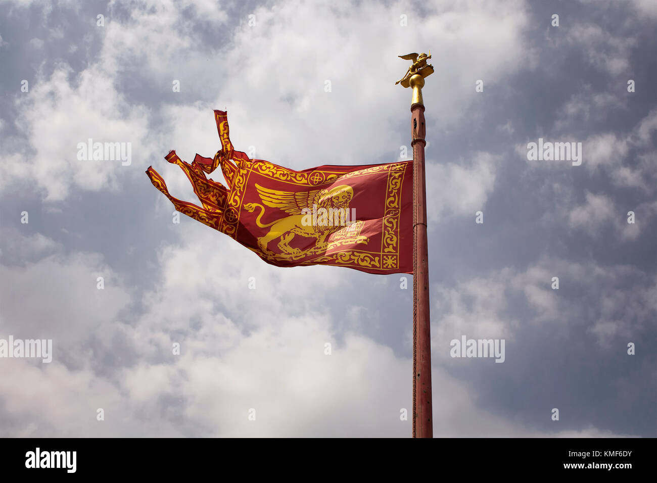 Vista de la histórica bandera veneciana saludando con fondo de cielo nublado. Foto de stock