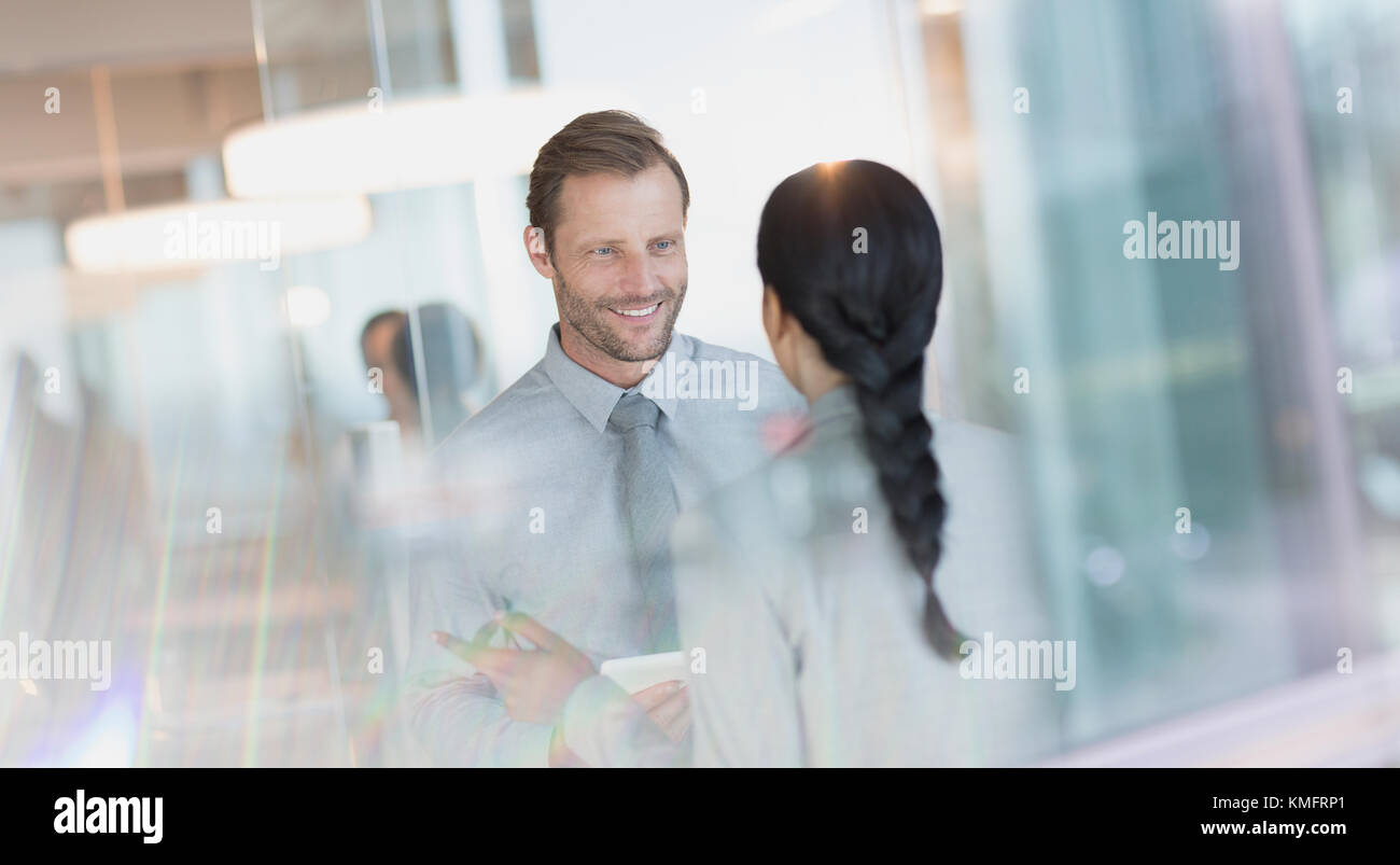 Empresario sonriente hablando a un colega en la oficina Foto de stock