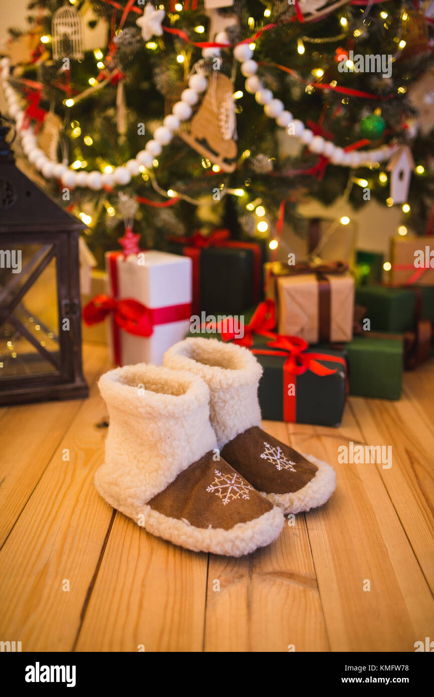 Par de zapatos cálido hogar de lana está cerca del árbol de navidad con  regalos en la casa en el piso de madera Fotografía de stock - Alamy