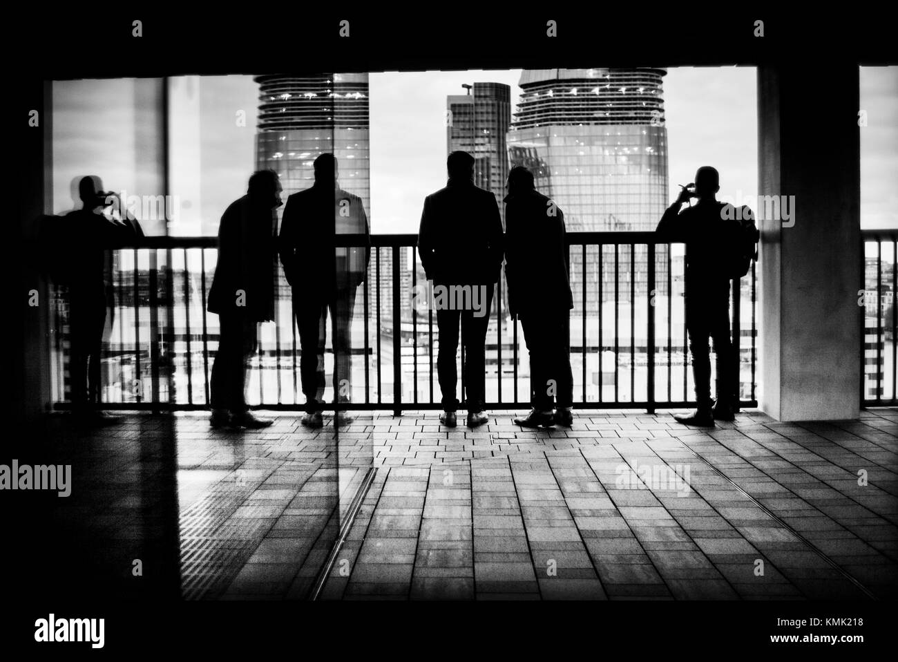 Silueta de tres irreconocible hombre y reflejado en un vaso de observar la ciudad desde un balcón. La Tate Modern, la ciudad, Bankside, London, UK Foto de stock