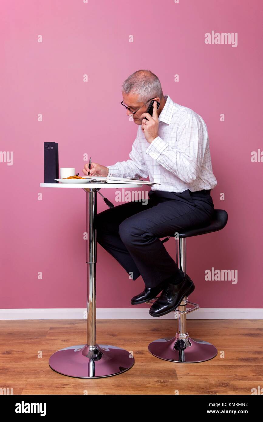 Empresario de vestimenta casual elegante sentado en un taburete de bar en  una cafetería trabajando por su almuerzo Fotografía de stock - Alamy