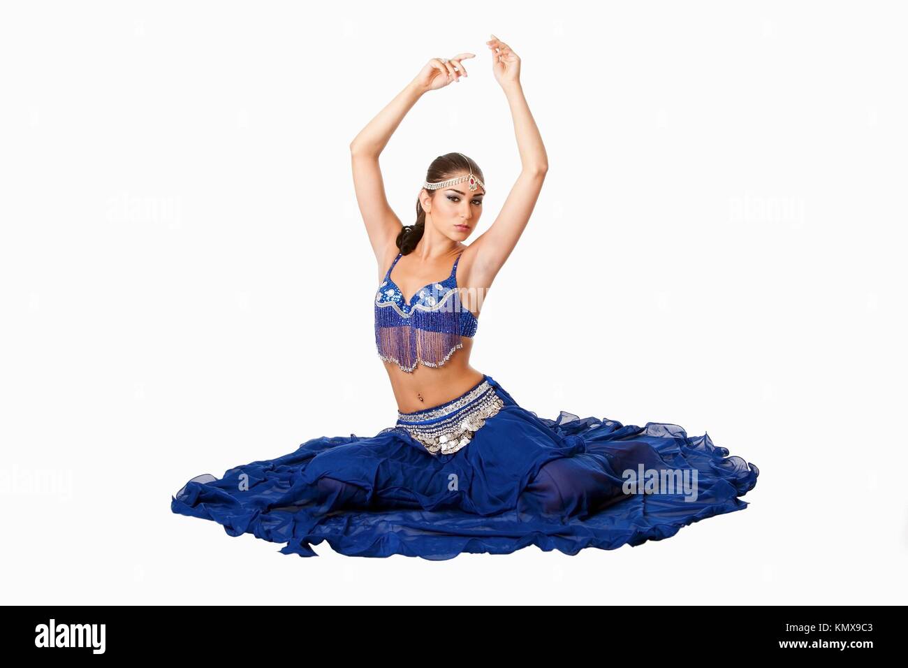 Hermosa egipcia Israelí de Oriente Medio libanés Belly Dancer ejecutante en falda azul y bra con los brazos en el aire sentado, aislado Foto de stock
