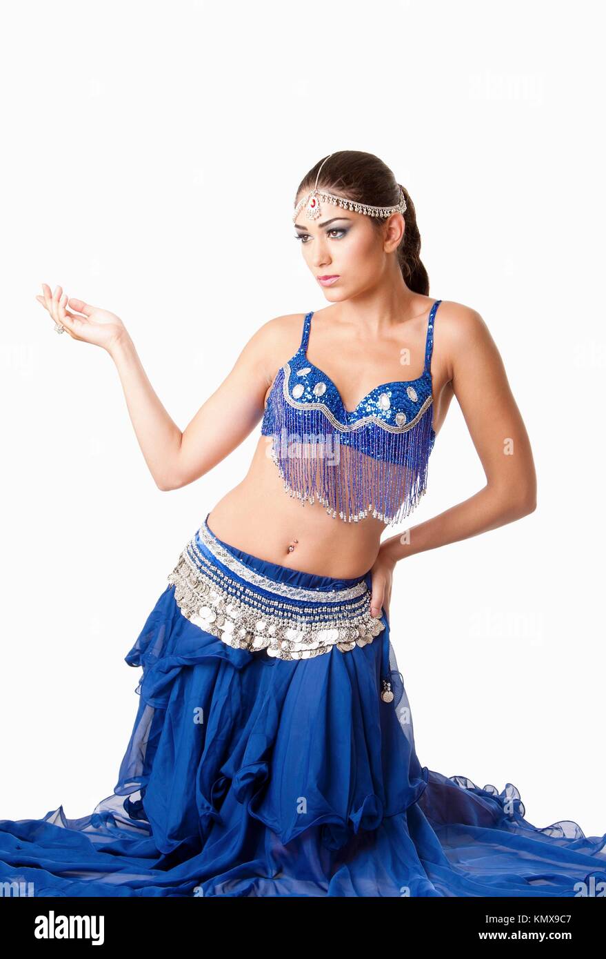 Hermosa egipcia Israelí de Oriente Medio libanés fashion Belly Dancer ejecutante en falda azul y bra sentada sobre las rodillas, aislado Foto de stock