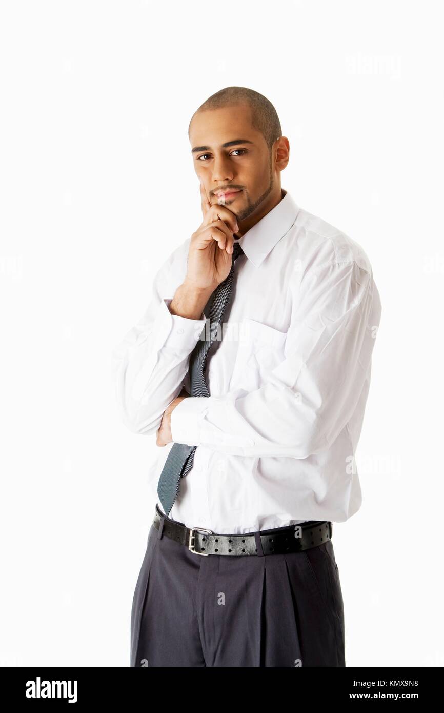 Apuesto hombre de negocios hispanos africanas con la camisa blanca, pantalón gris y corbata, de pie con las la barbilla pensando, Fotografía de stock Alamy
