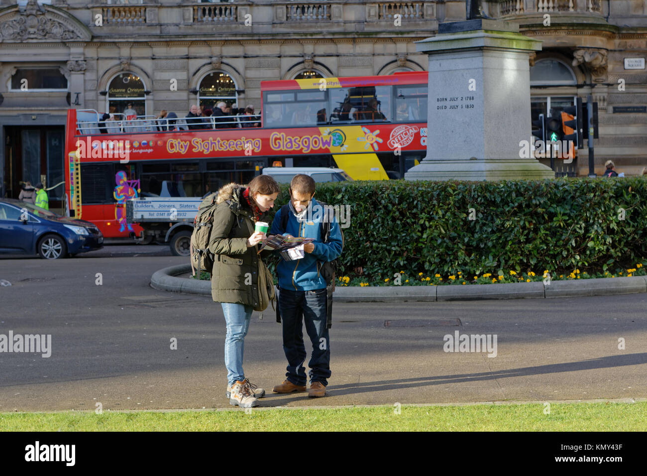 Los turistas extranjeros mochileros autobús turístico de la ciudad de Glasgow leer mapa chico chica par George Square, Glasgow, Glasgow, Reino Unido Foto de stock