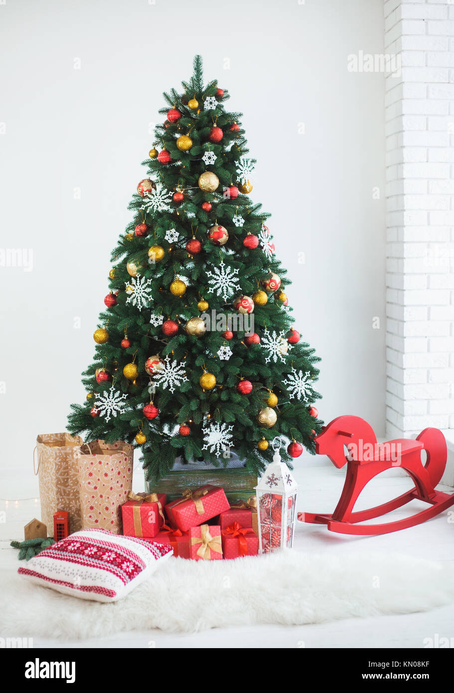 Árbol de Navidad verde hermoso bellamente decorado para la celebración.  Muchos cuadros envueltos en papel rojo festivo bajo las ramas de pino.  Color vertical p Fotografía de stock - Alamy