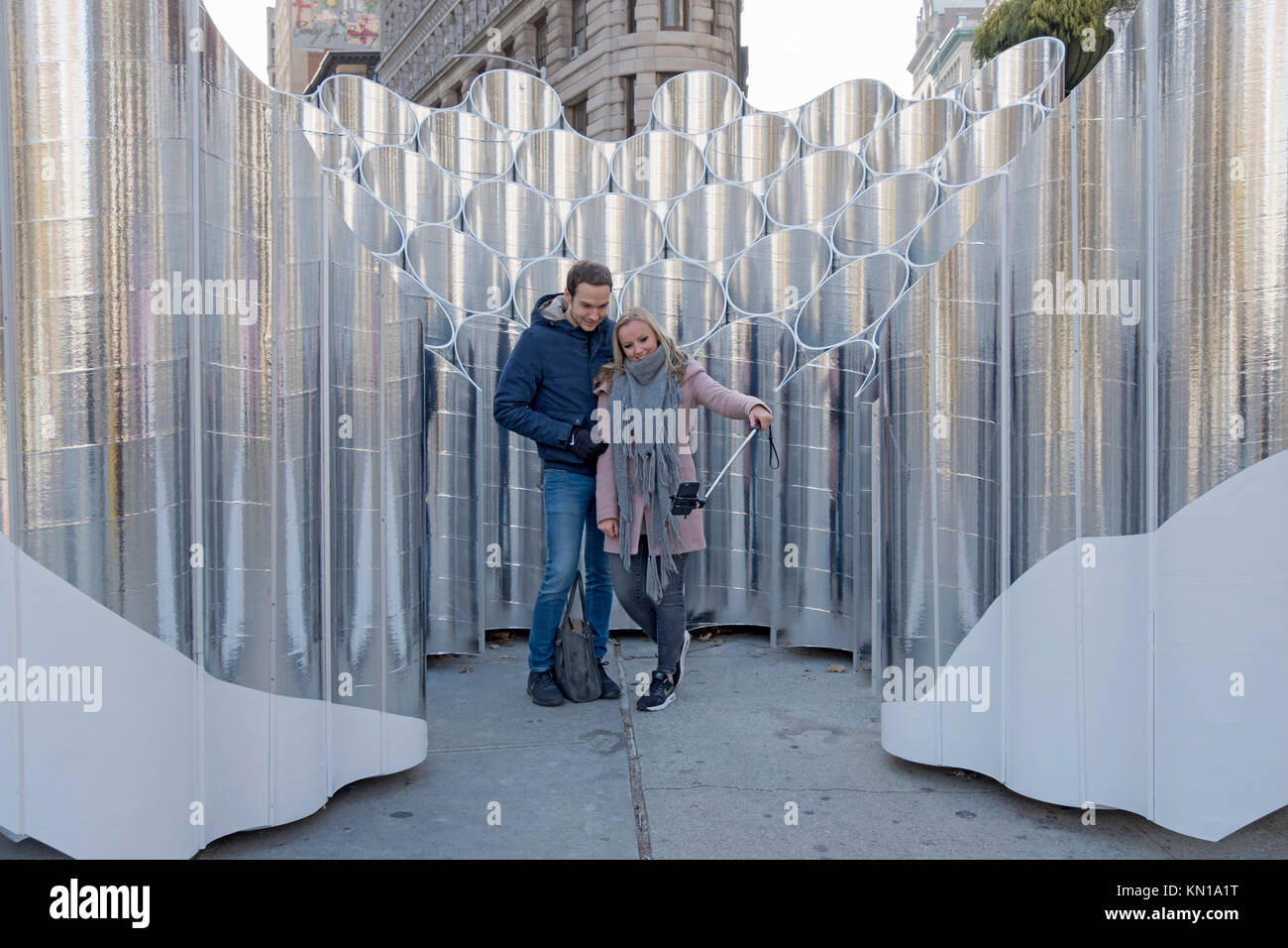 Los turistas alemanes, posando para las fotos delante de la escultura Flatiron reflexiones de futuro expresión en el Flatiron District de la ciudad de Nueva York. Foto de stock