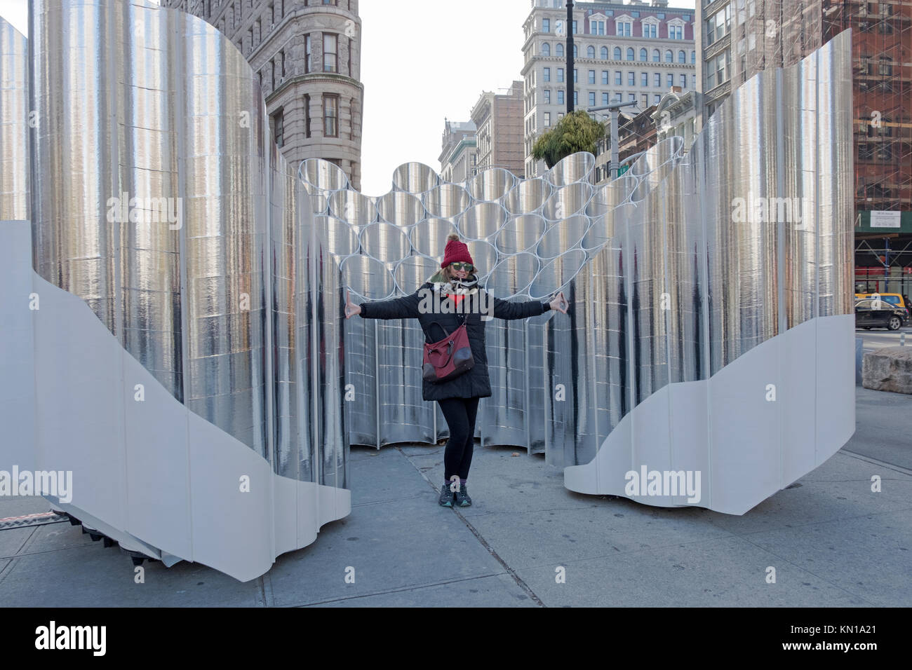 Un turista posando para fotos en frente de la escultura Flatiron reflexiones de futuro expresión en el Flatiron District de la ciudad de Nueva York. Foto de stock