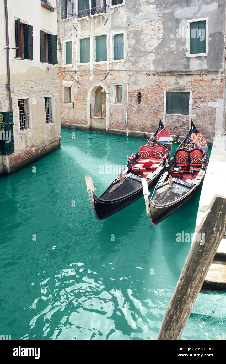 Bello escorzo de edificios en un pequeño canal en Venecia, con detalle de dos góndola. Foto de stock