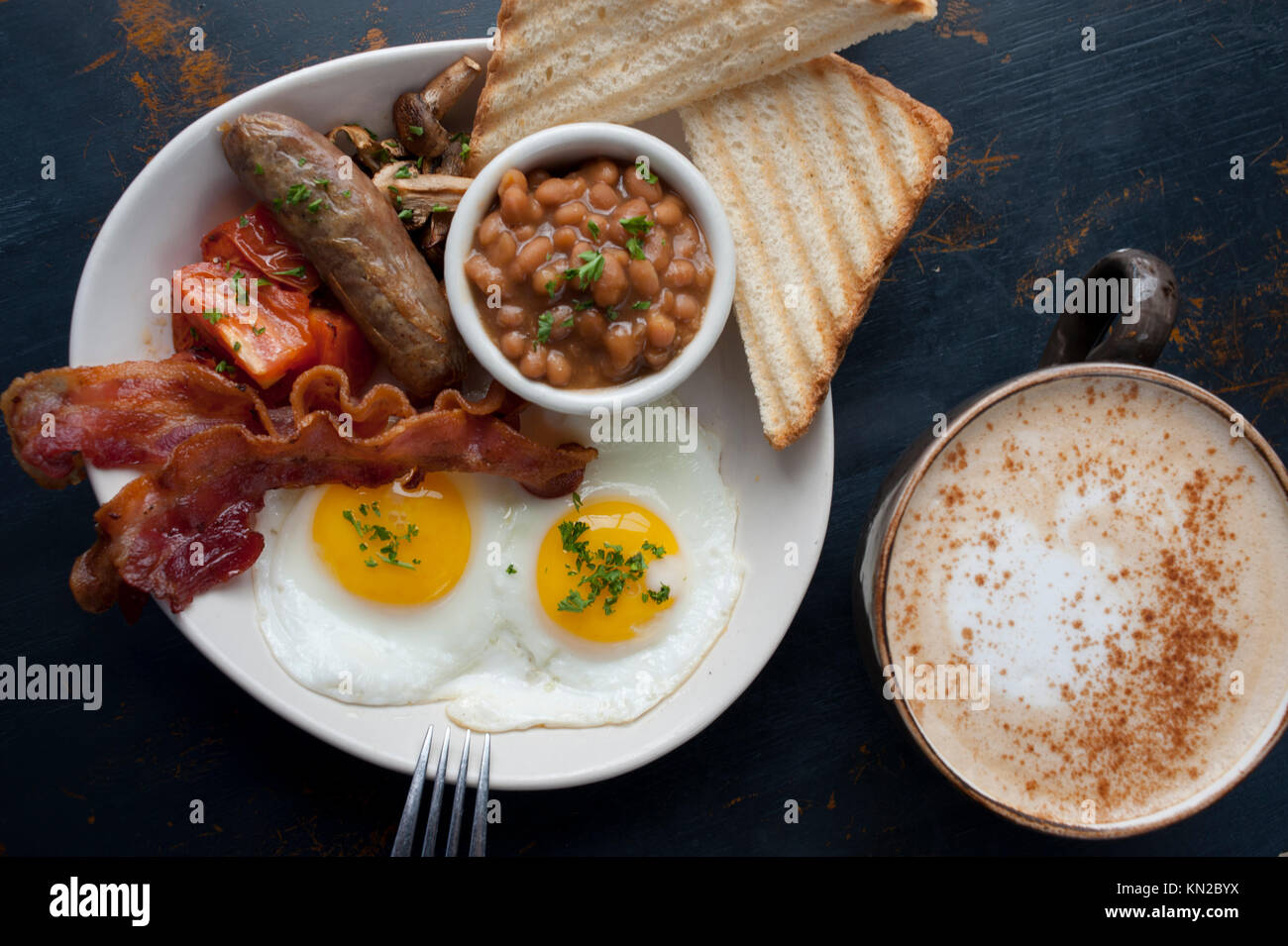 Comida un clásico desayuno inglés completo de huevos bacon o salchichas salchichas frijoles tomates setas y tostadas con café Foto de stock