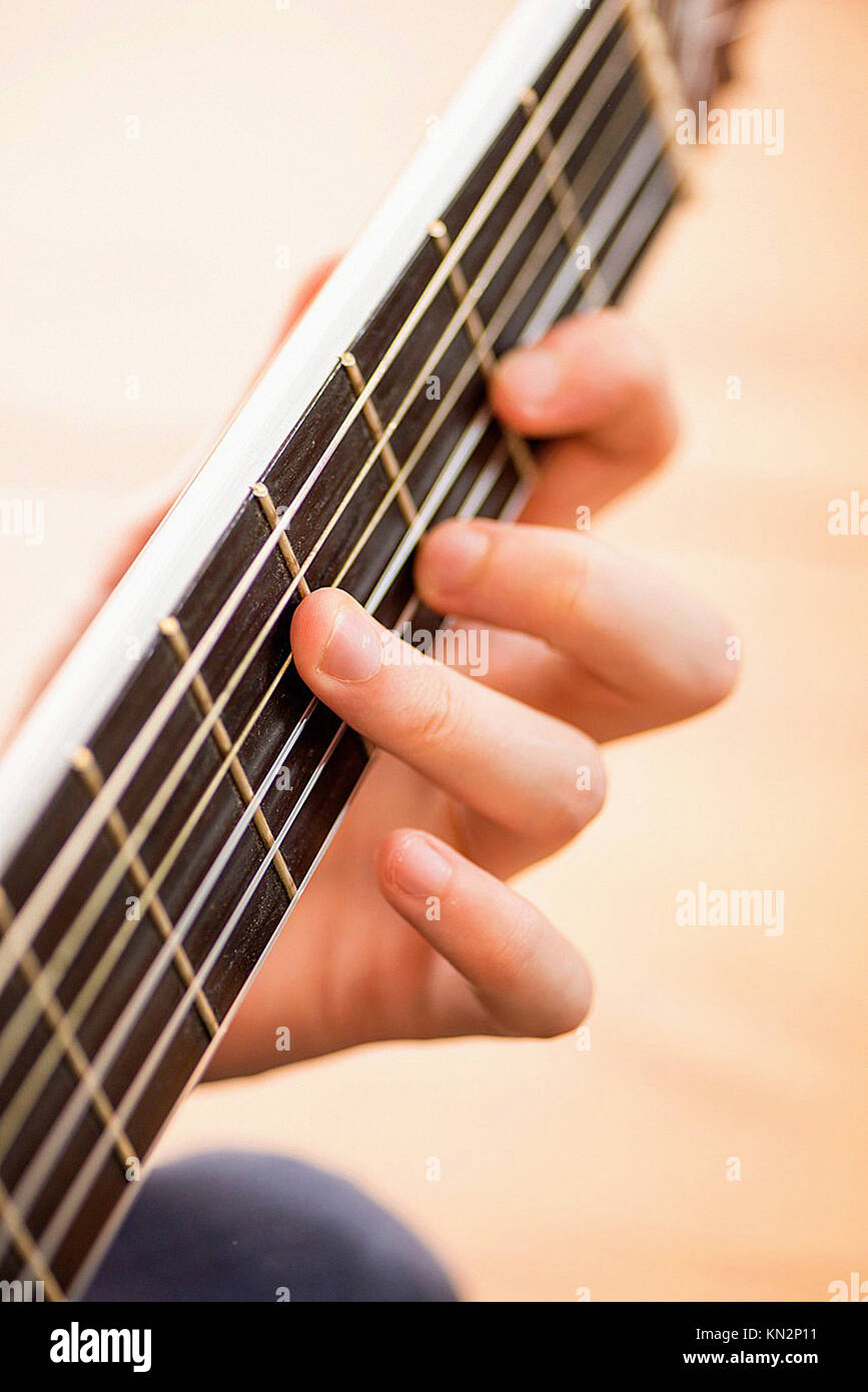Las cadenas y los dedos del joven al tocar un acorde en la guitarra  acústica de madera Fotografía de stock - Alamy