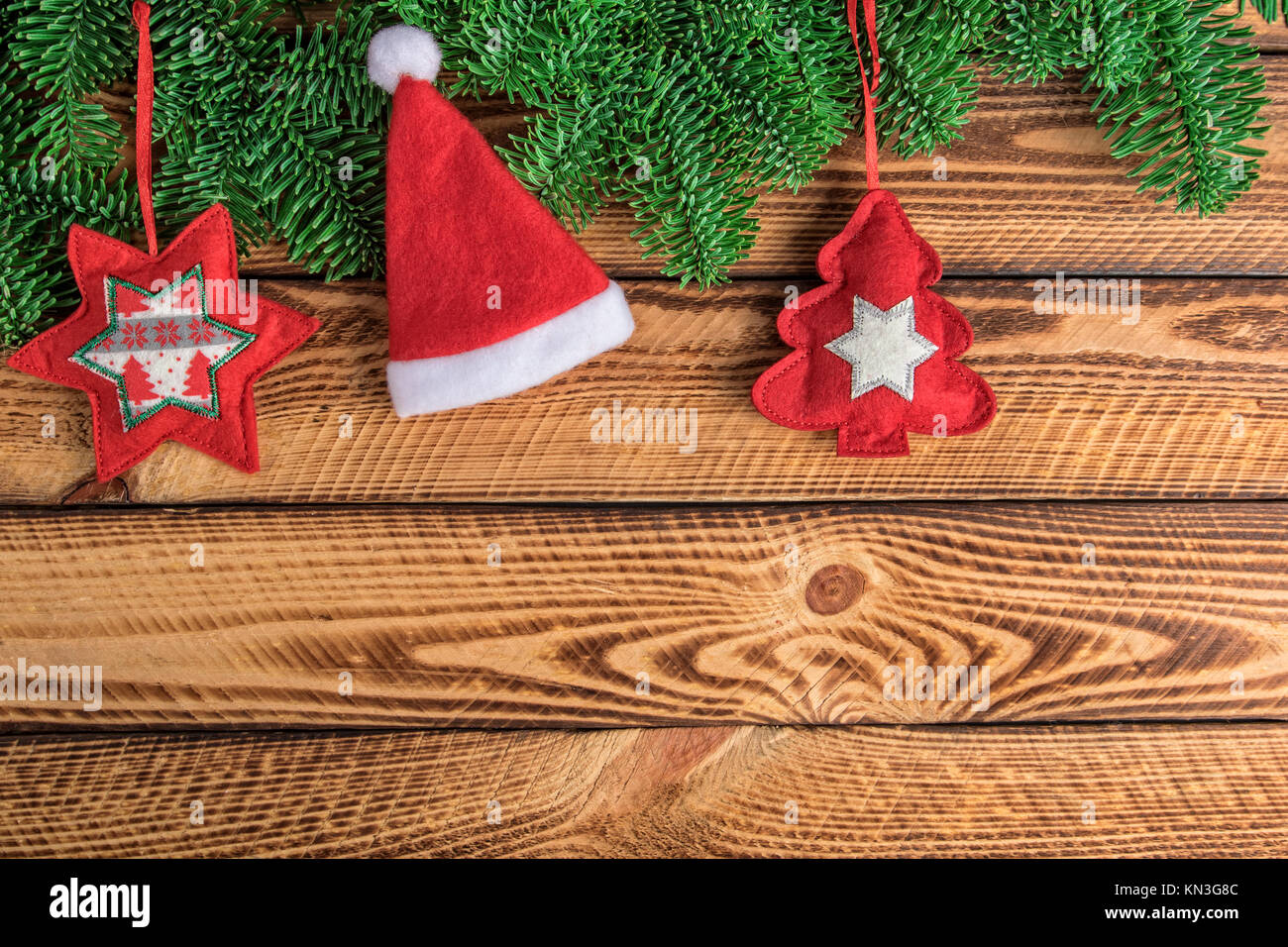 Fondo de navidad con el gorro de Papá Noel y la rama de abeto rojo  decoración fieltro sobre tablones de madera oscura Fotografía de stock -  Alamy