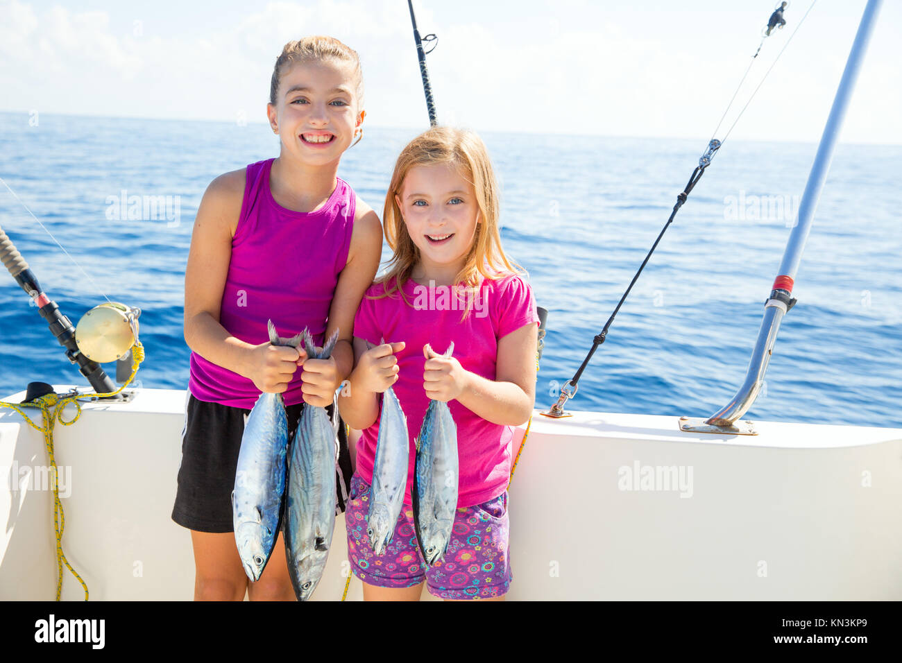 Feliz atún pescadoras kid chicas en barco con peces curricán capturas. Foto de stock