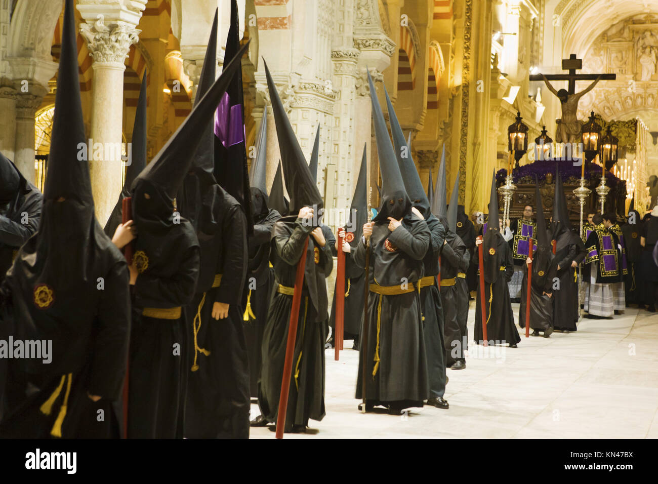 La Pascua los nazarenos de túnica negra esperando en el interior de la Mezquita de Córdoba, justo antes de comenzar la procesión. Llevan velas y vistiendo el típico Foto de stock
