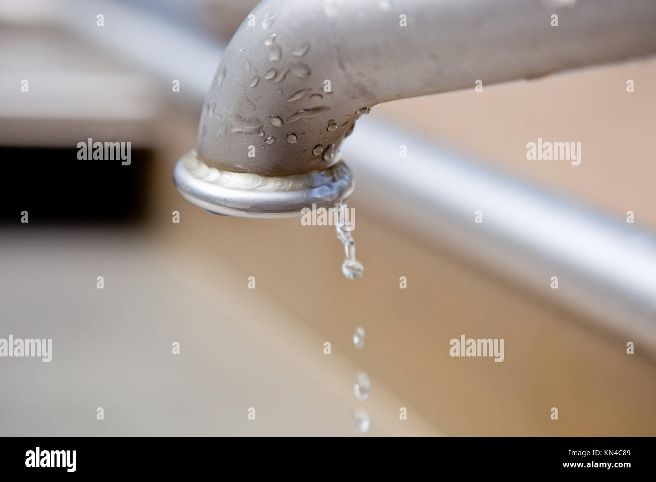 Las gotas de agua que fluye desde el metal de agua potable. Foto de stock