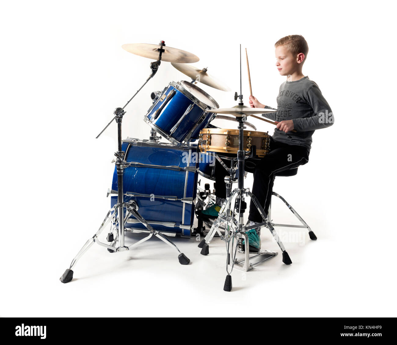 Yount jovencito rubio en drum kit en estudio con fondo blanco. Foto de stock
