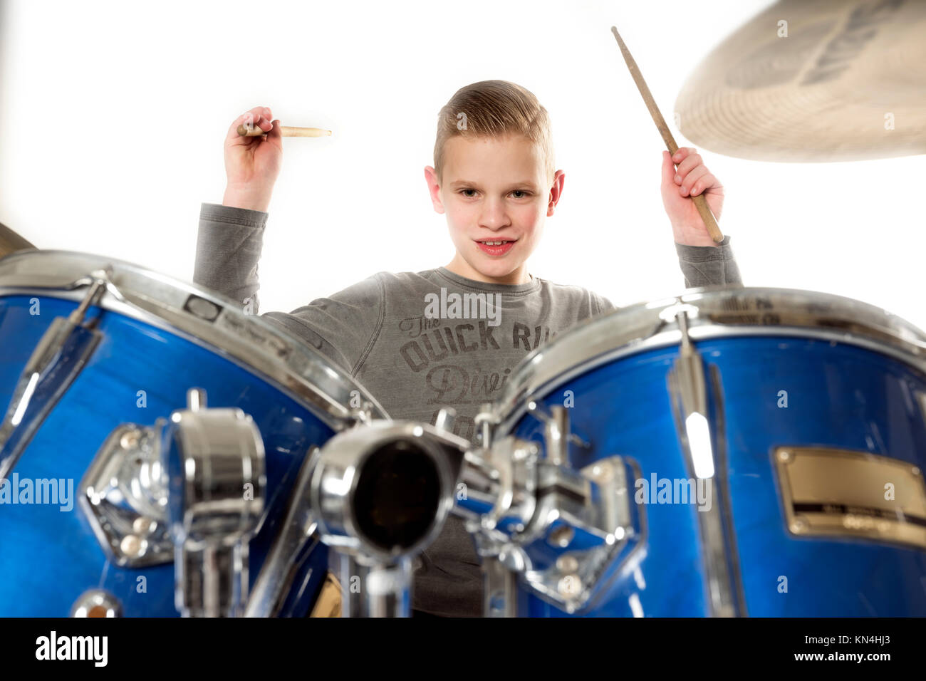 Yount jovencito rubio en drum kit en estudio con fondo blanco. Foto de stock