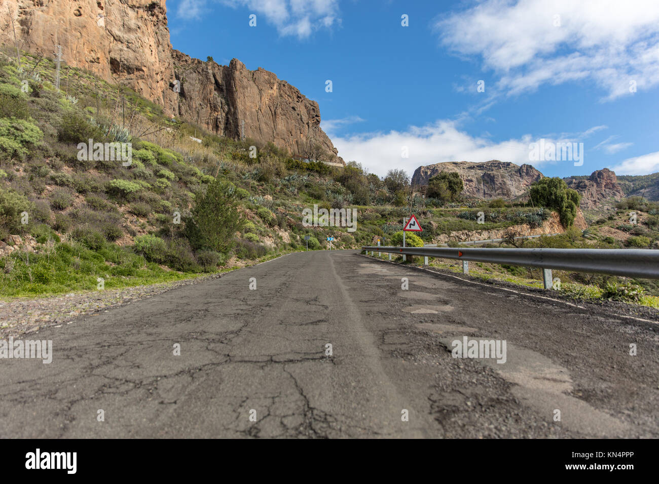 Calle con barandilla y curva doble señal de tráfico en carreteras de montaña en Gran Canaria. Foto de stock