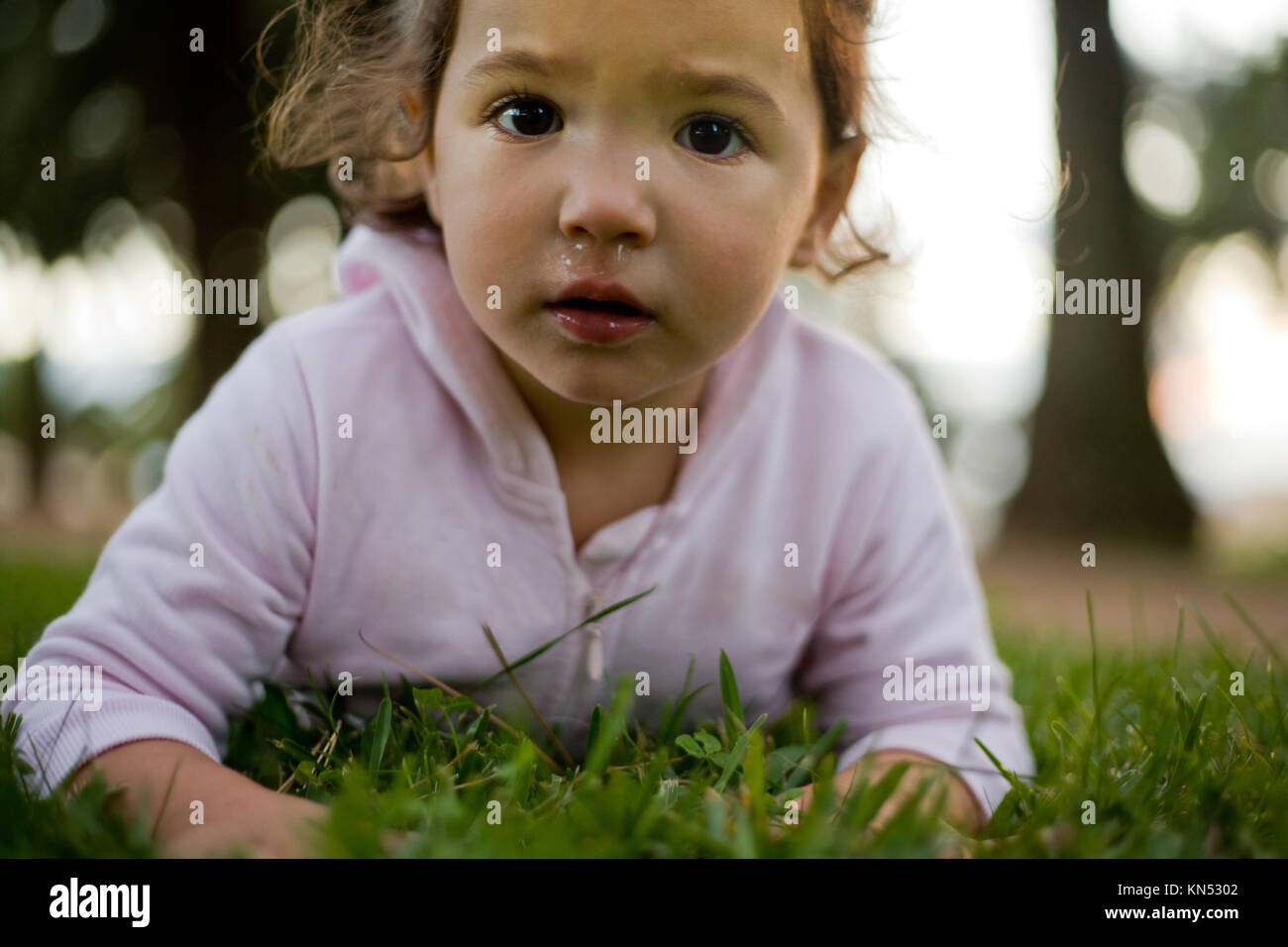 Cerca de una niña mirando a la cámara con la nariz llena de moco. Foto de stock