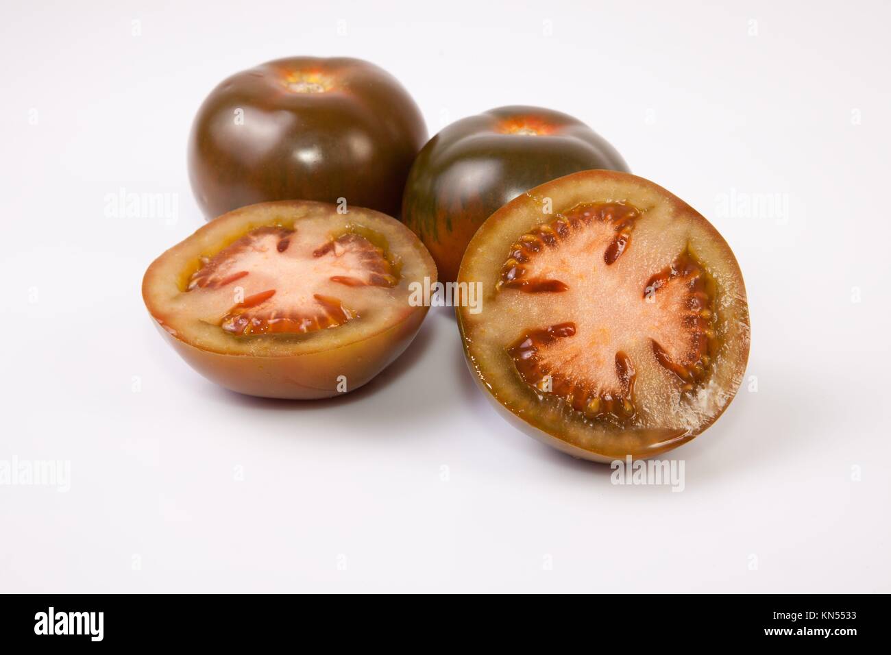 Verde oscuro tomates kumato, enteras o en rodajas. Aislado sobre fondo blanco. Foto de stock