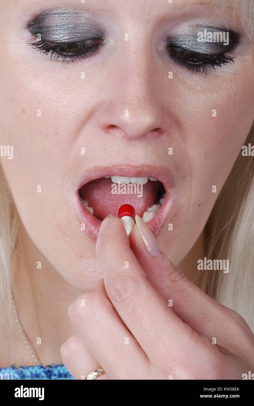 Mujer sosteniendo un analgésico entre los dedos. Foto de stock
