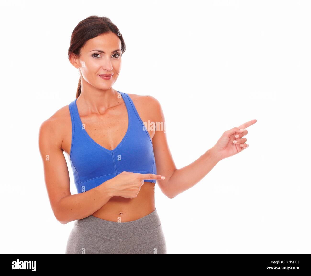 Mujer adulta formación con vitalidad y apuntando a su izquierda en el fondo - copyspace aislados. Foto de stock