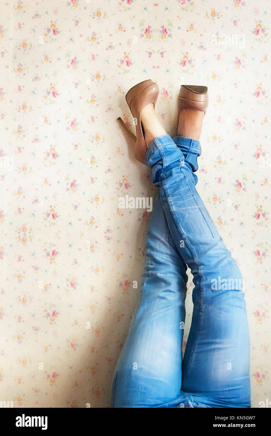 Las piernas de una mujer en pantalones vaqueros contra la pared Fotografía  de stock - Alamy