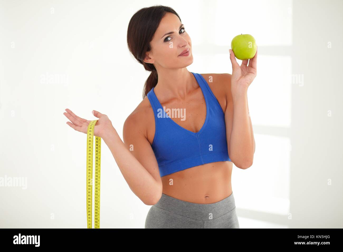 Conscientes de la Salud mujer en ropa deportiva de perder peso con la fruta mientras mira. Foto de stock