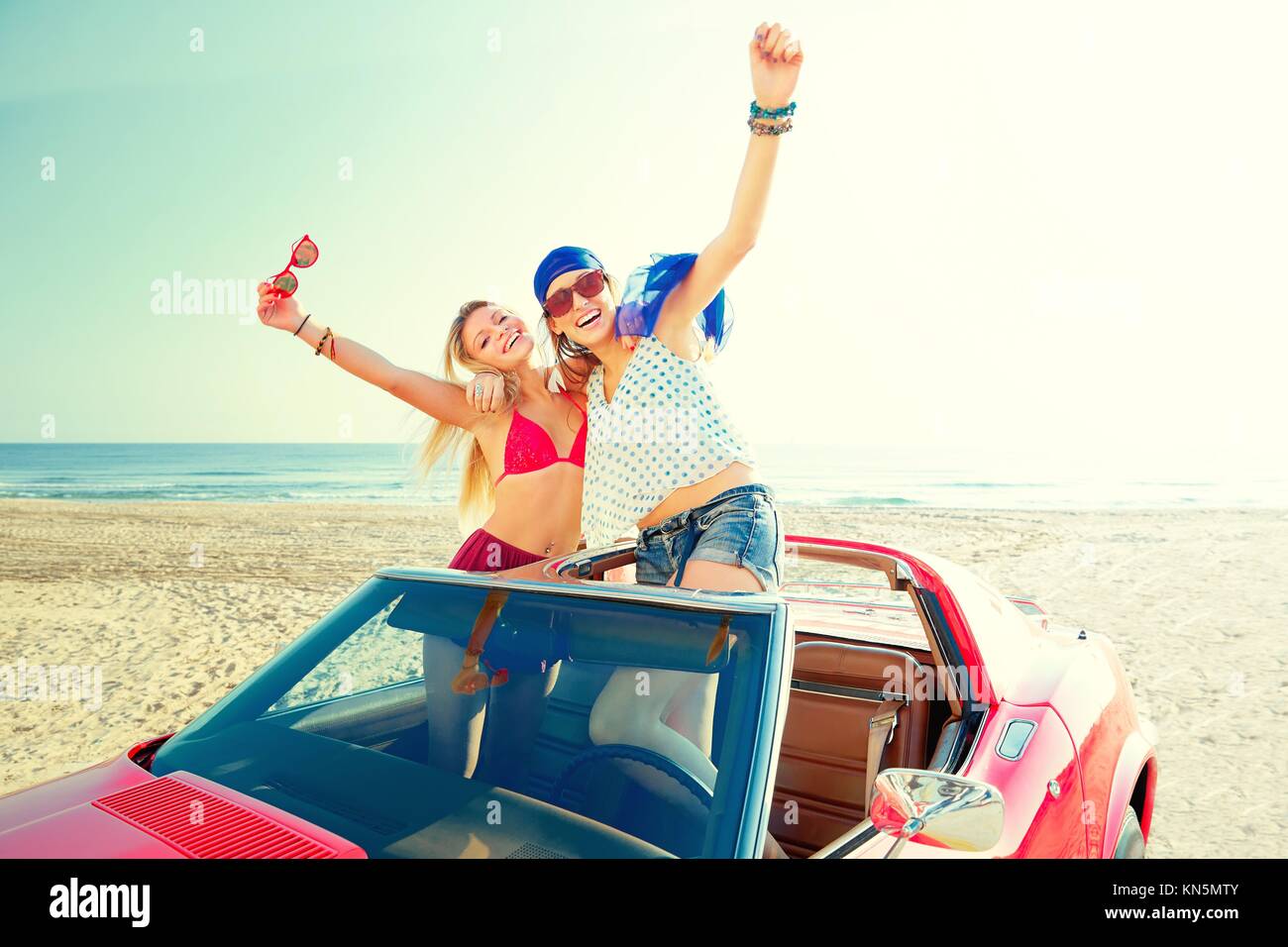 Hermosa fiesta amigo chicas bailando en un coche en la playa feliz. Foto de stock