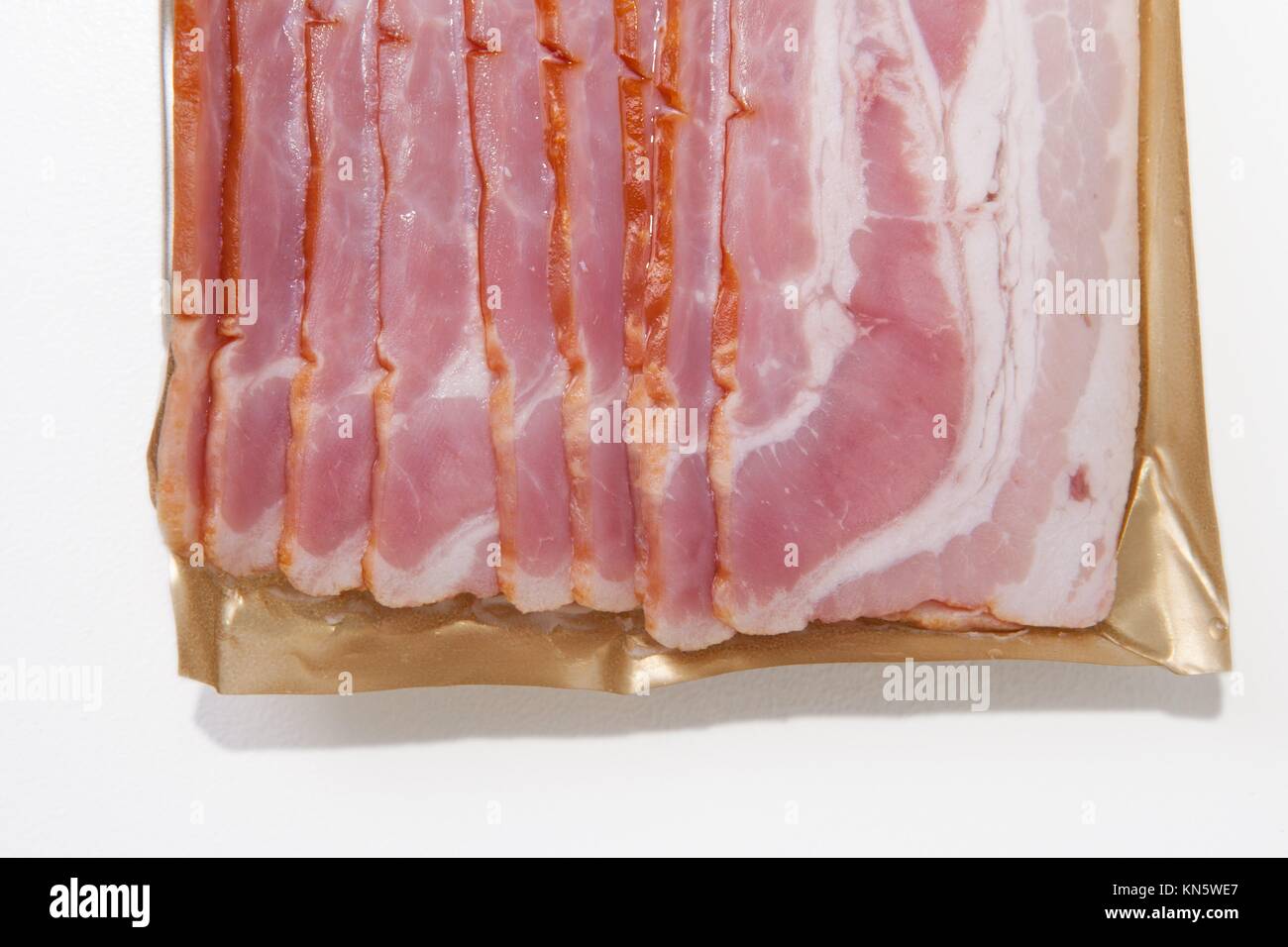 Bacon cortes en el paquete, aislado sobre fondo blanco. Foto de stock