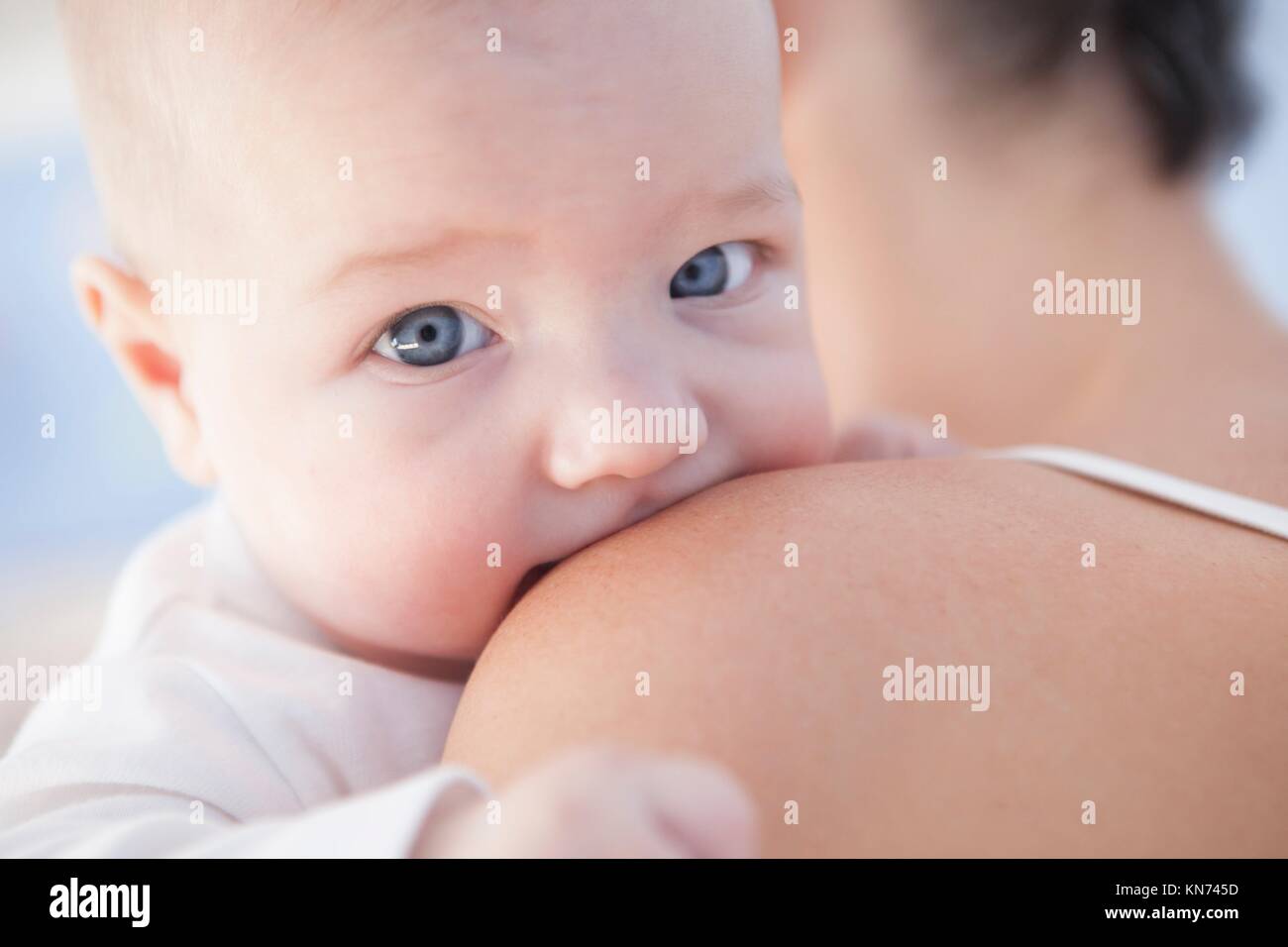 Retrato de un bebé de cuatro meses sobre el hombro de su mamá. Foto de stock