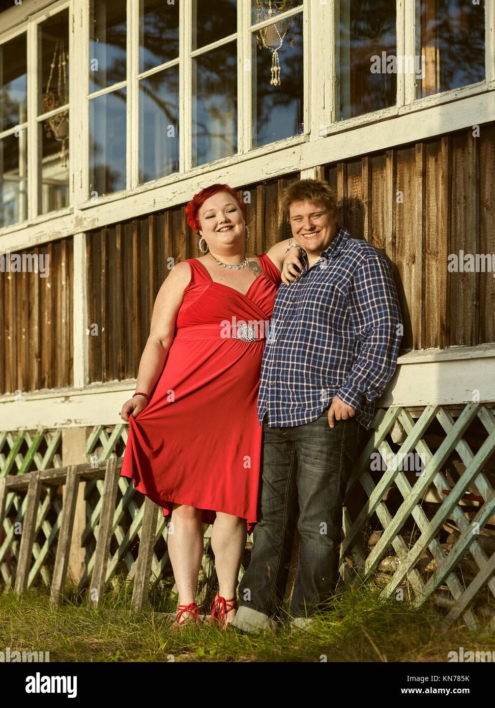Encantadora pareja juntos delante de la pared de madera, la cálida luz del atardecer de verano. Foto de stock