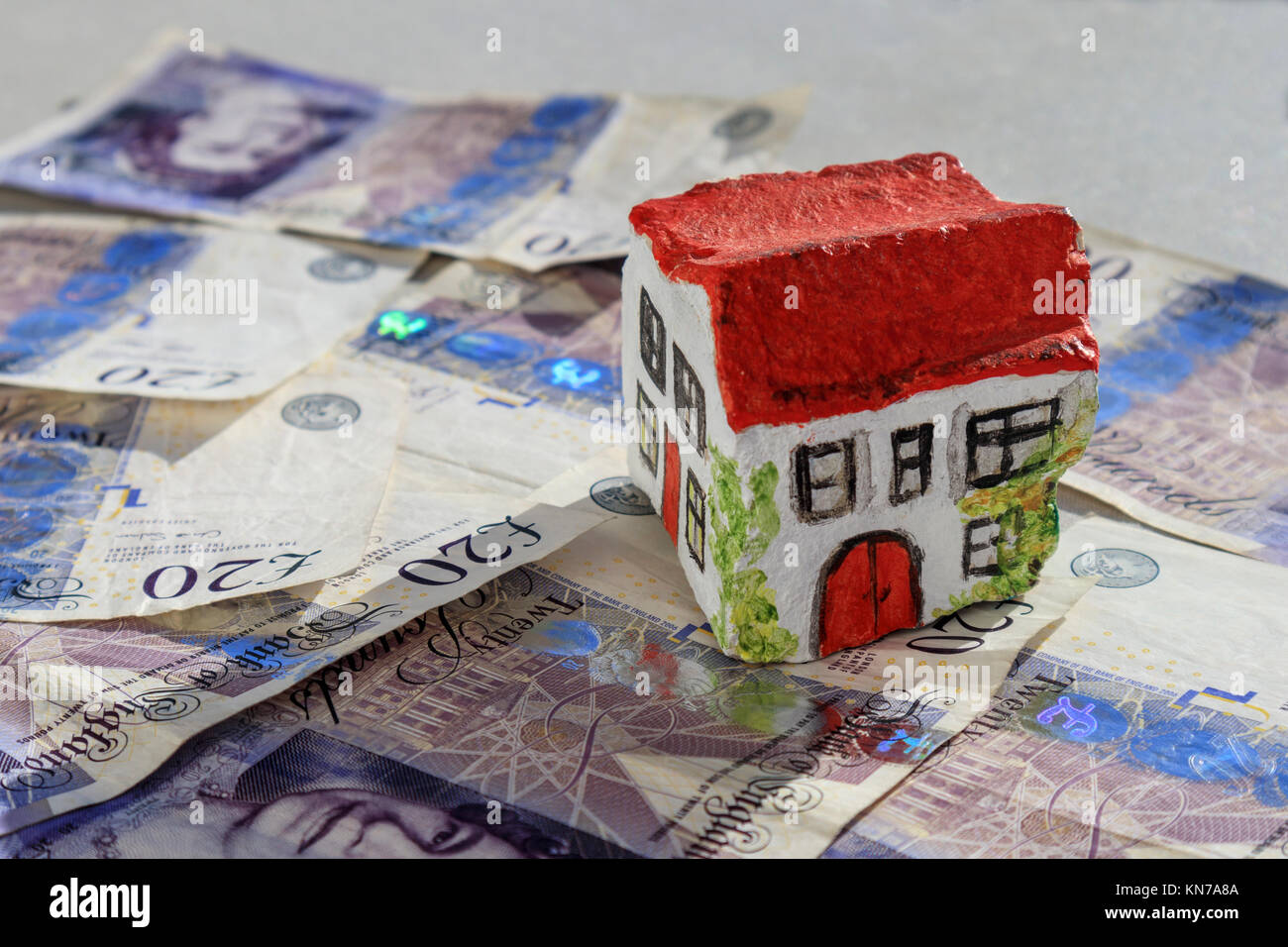 Casa de piedra pintada a mano sentado en 20 libras notas moneda británico sugiriendo el ahorro en el impuesto de timbre Foto de stock