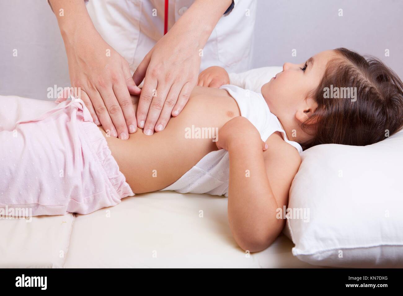 Pediatra haciendo el examen del abdomen con las manos. Foto de stock