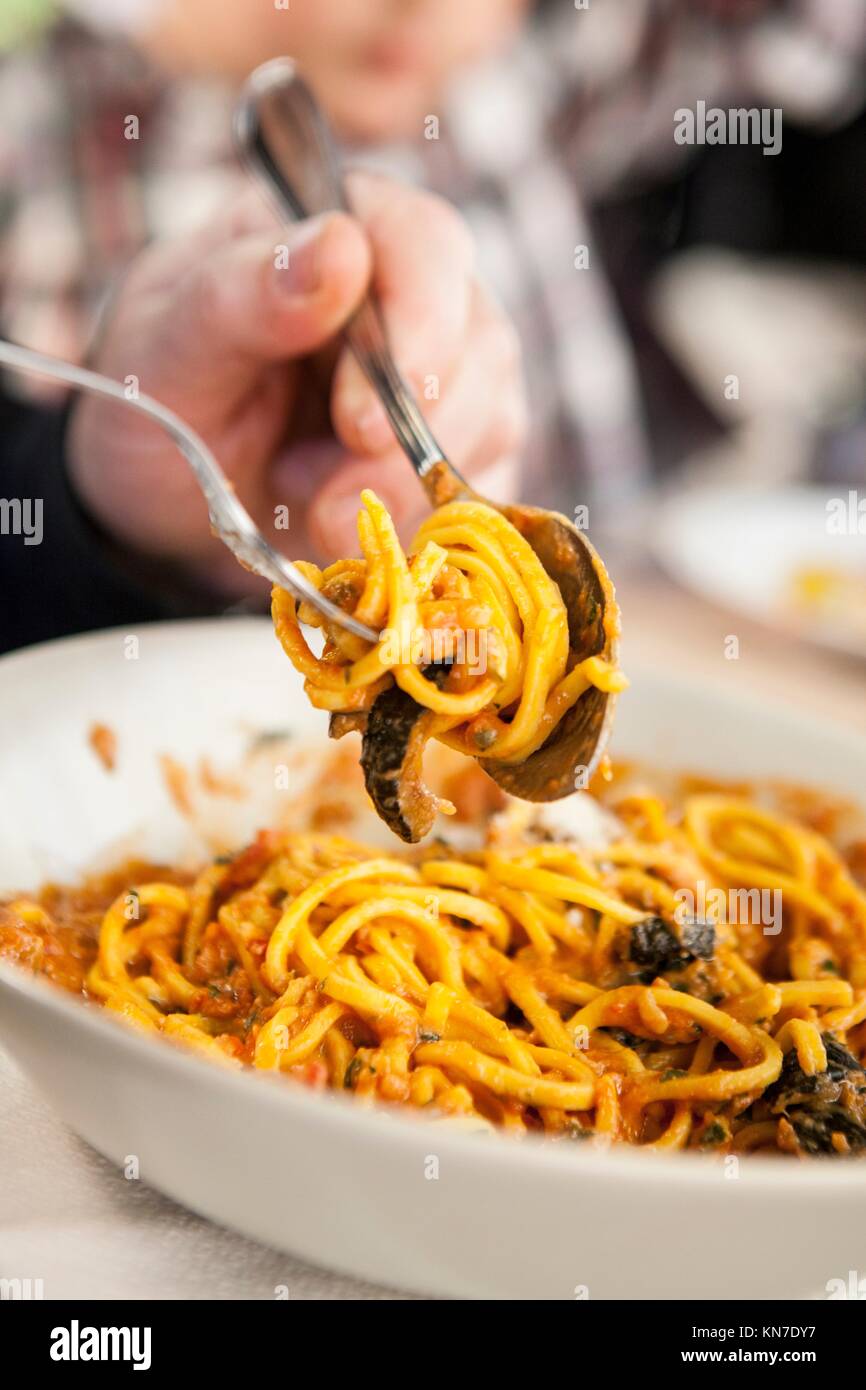 Cena guest enrollando espaguetis en una horquilla. Closeup. Foto de stock