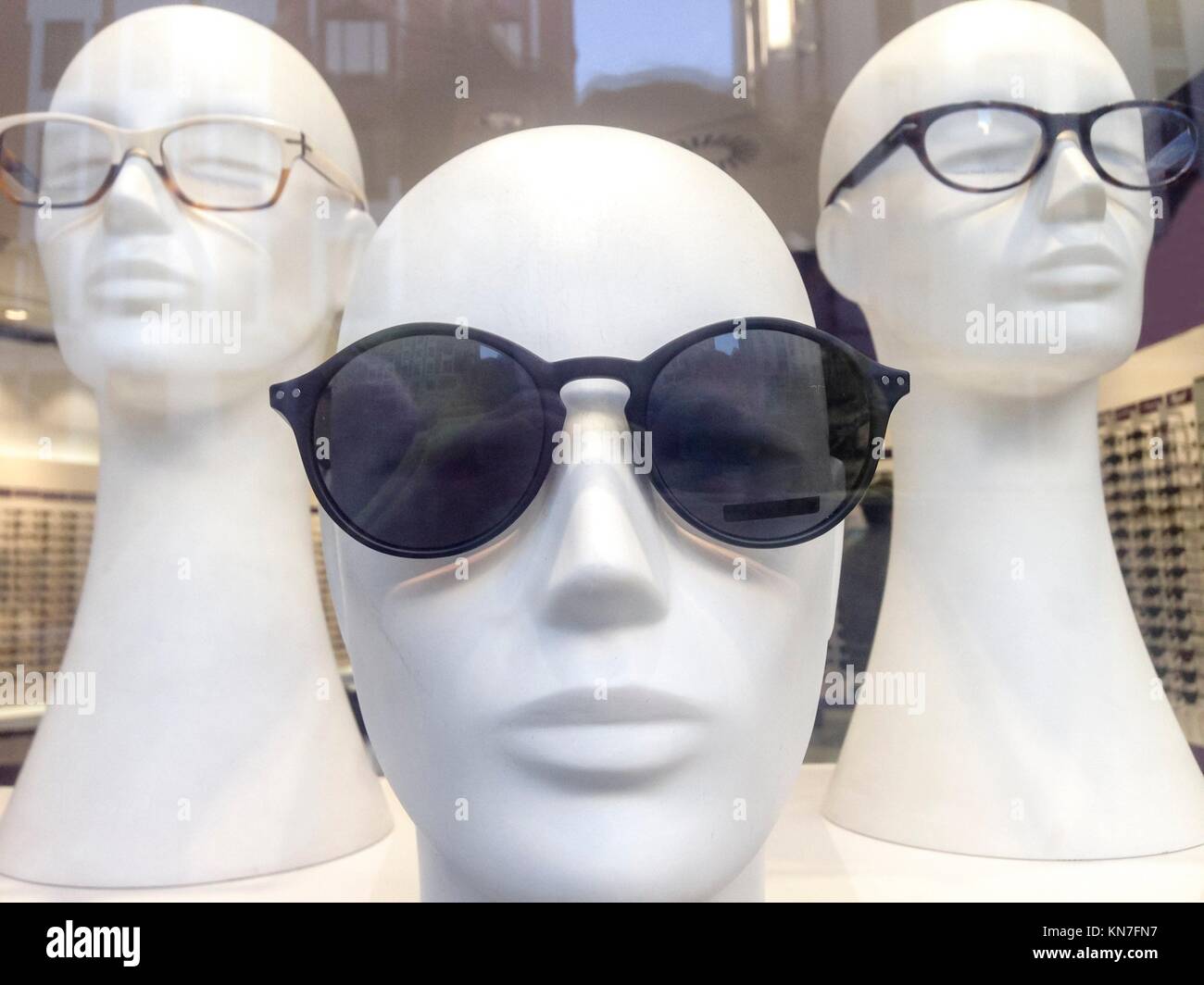 Tres cabezas de maniquí en el escaparate con reflexiones urbanas. Foto de stock