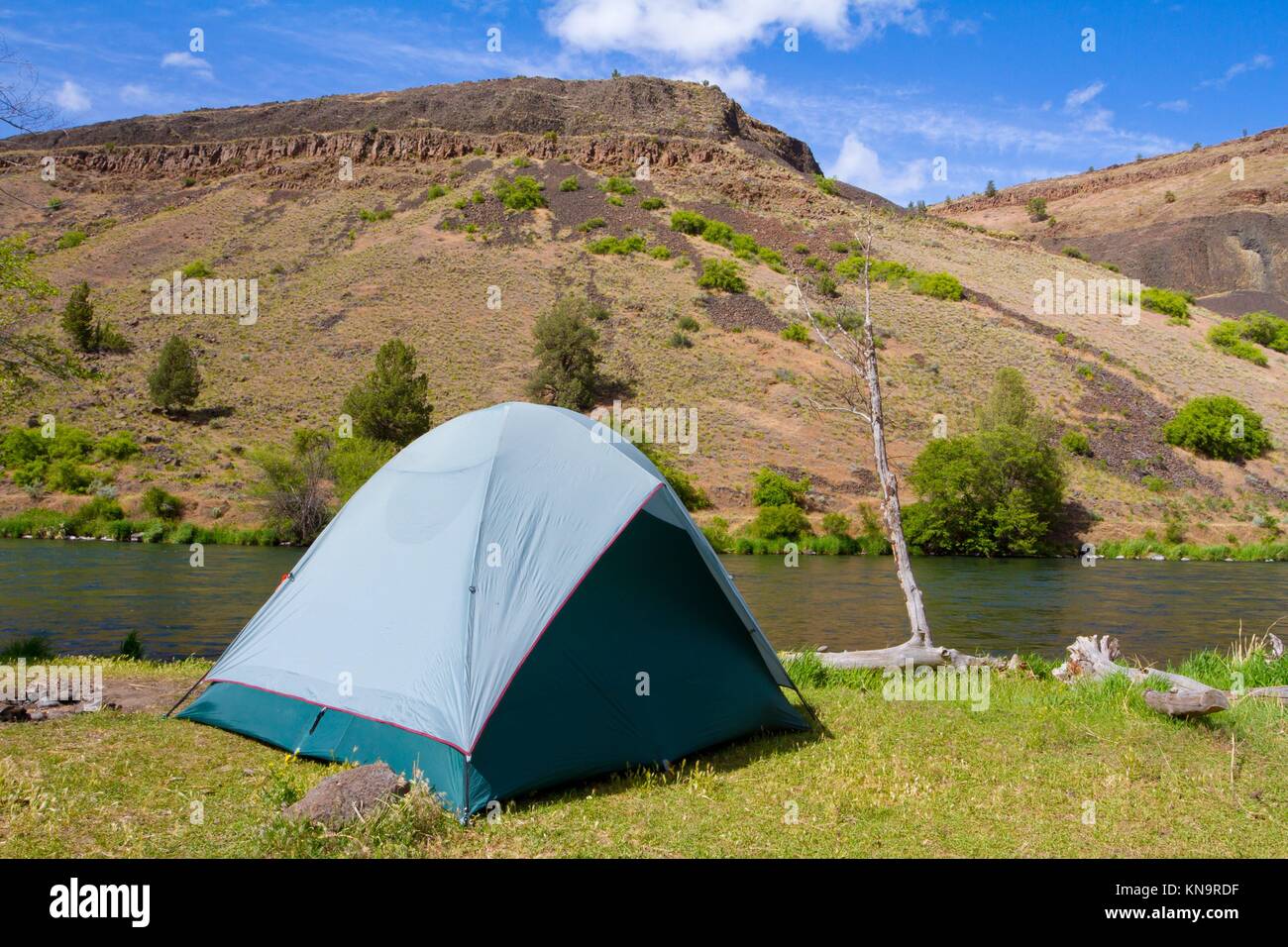 Una carpa camping rústico en el río de Deschutes en Oregon muestra una configuración de tienda de campaña junto a un barco y el río. Este formulario es un camping de flotación. Foto de stock