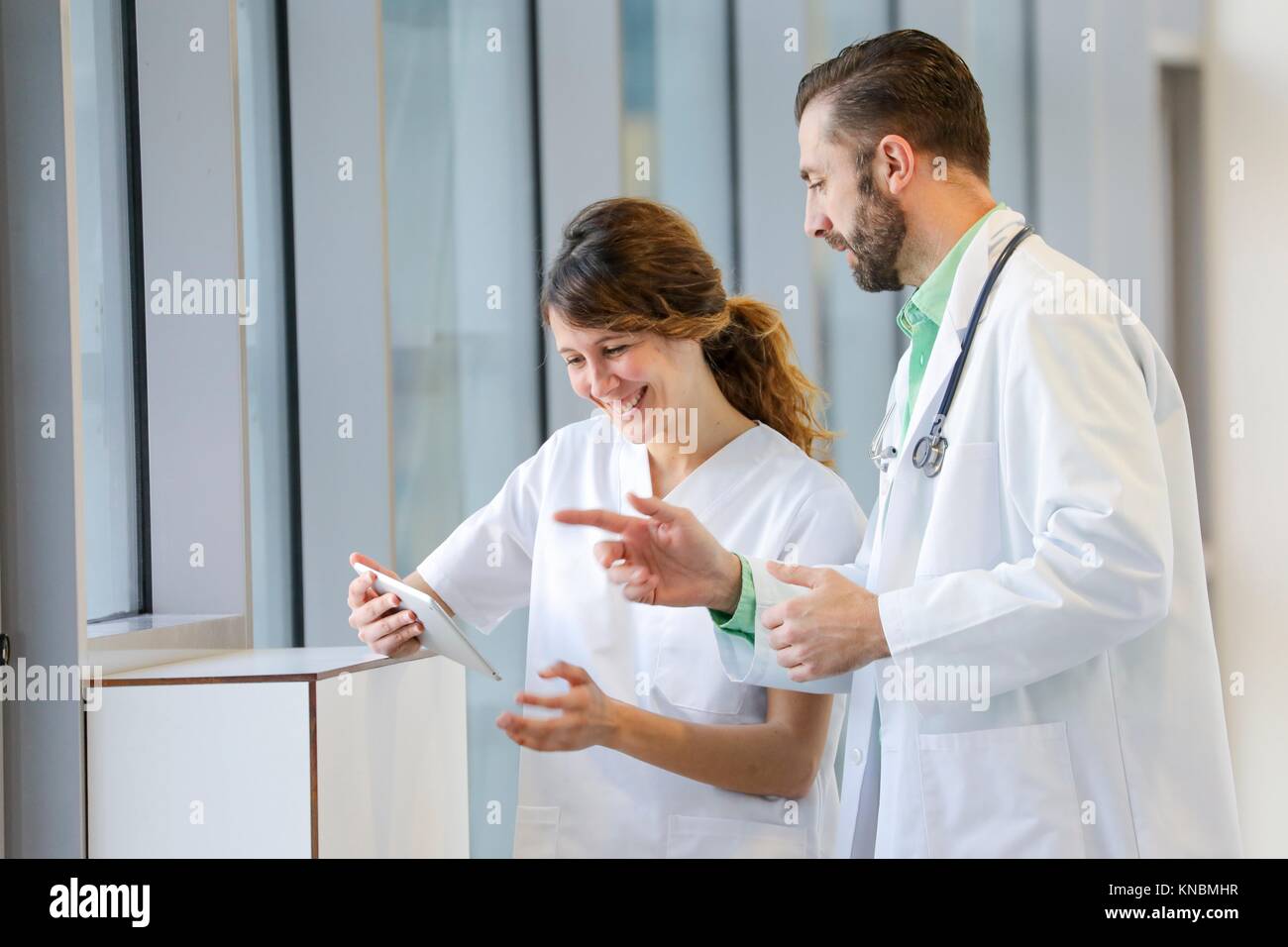 Un médico y una enfermera con tablet hablando en el pasillo, Hospital Foto de stock
