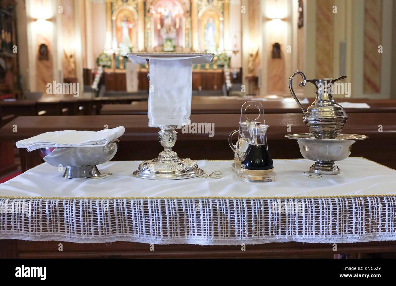 Litúrgica católica objetos mostrados en la tabla en la iglesia. Cáliz, comunión de obleas, vino, agua, ewer y Cuenca. Foto de stock