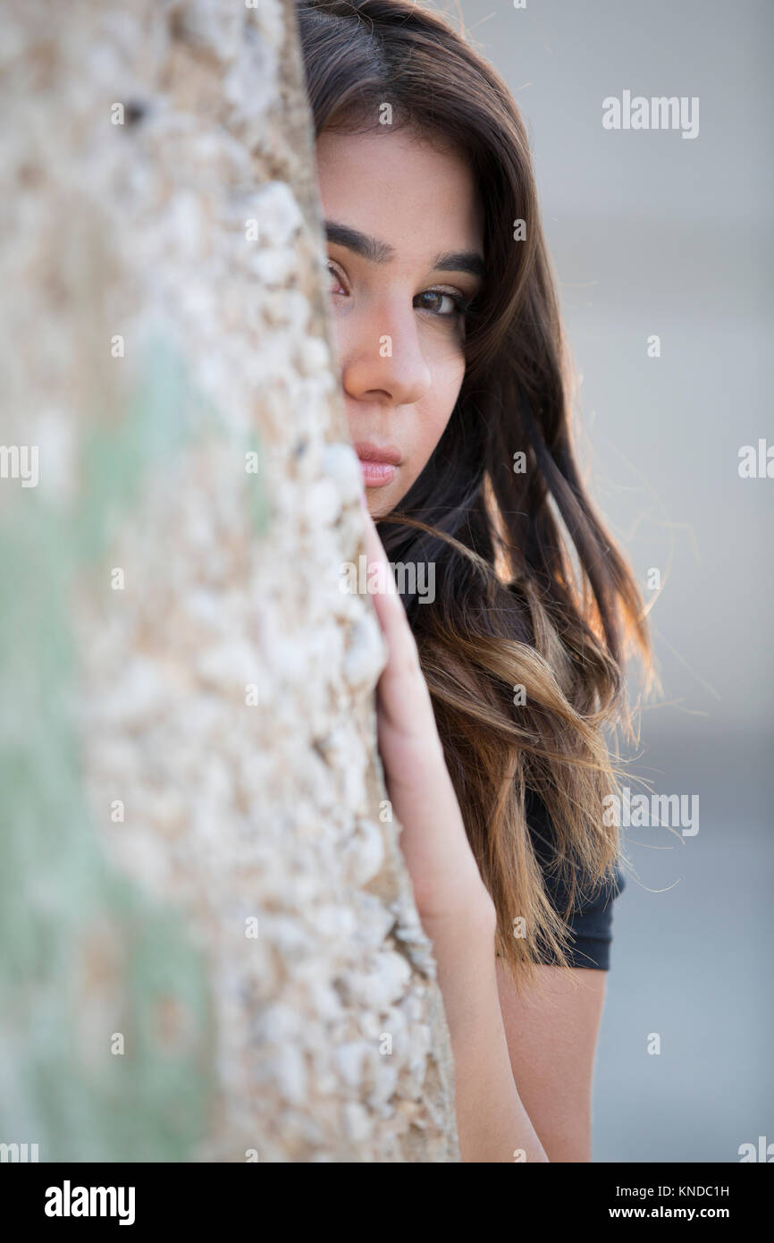 Joven Scaered escondido detrás de la pared Foto de stock