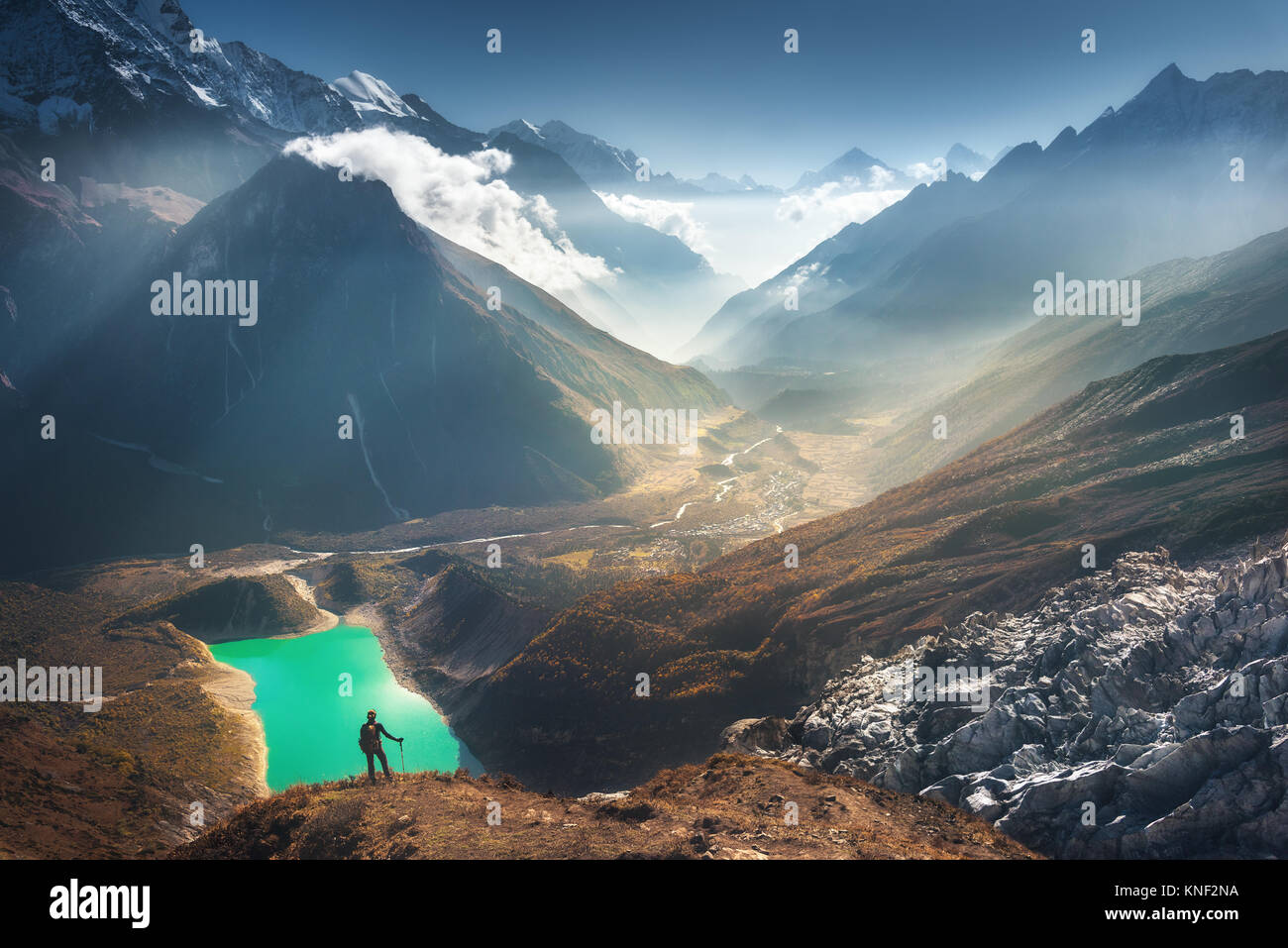 Mujer joven de pie sobre el pico de la montaña y mirar en el hermoso valle de montaña con lago, río y las colinas al atardecer. Paisaje con muchacha, rocas en Foto de stock