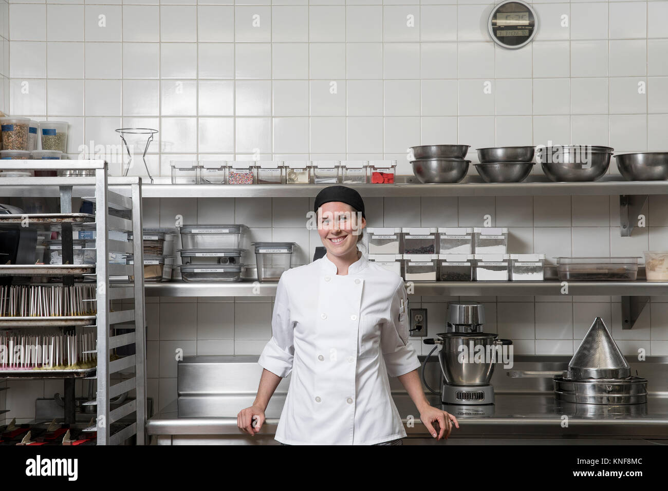Retrato de chef en cocina comercial mirando a la cámara sonriendo Foto de stock