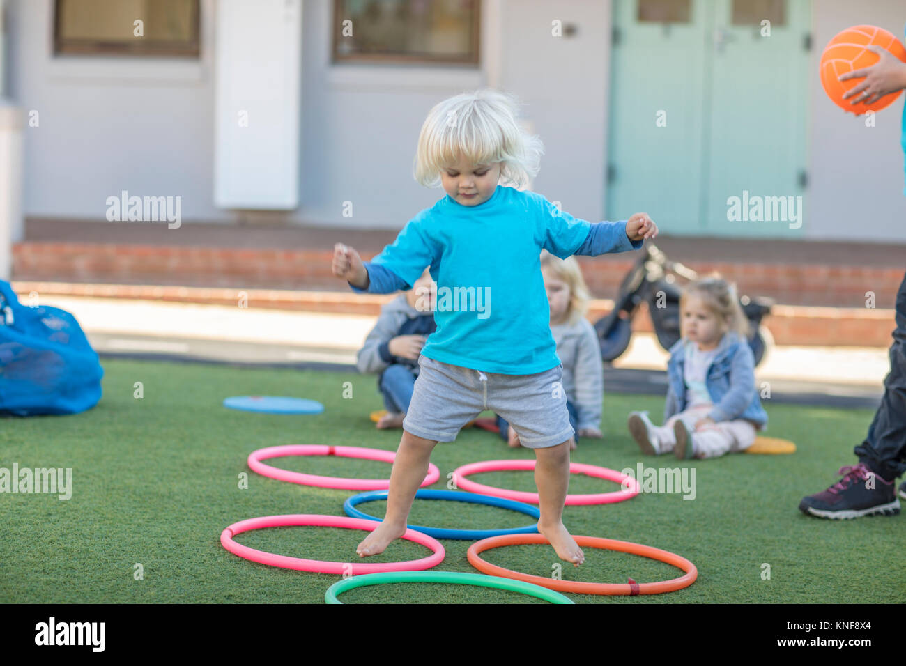 Niña de la escuela preescolar, saltando por encima de los aros de plástico  en el jardín Fotografía de stock - Alamy