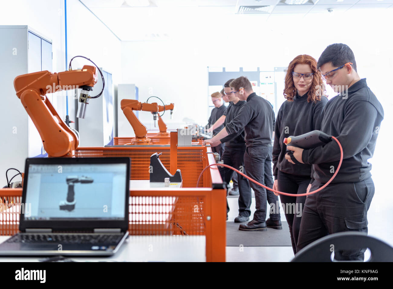 Los aprendices de robótica utilizando el test robots industriales en instalaciones de robótica Foto de stock