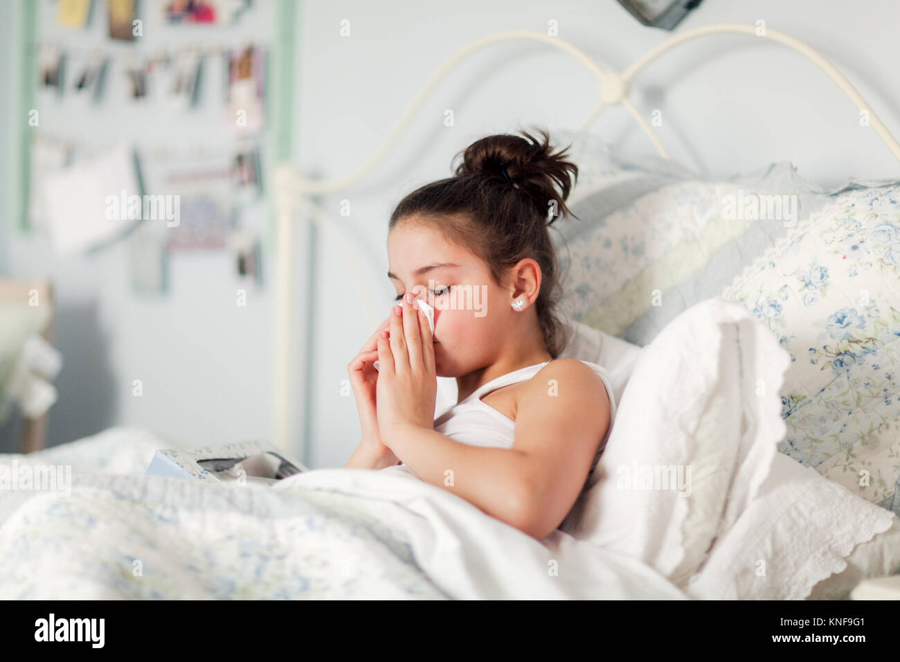 Chica en la cama sonarse la nariz en el pañuelo Foto de stock