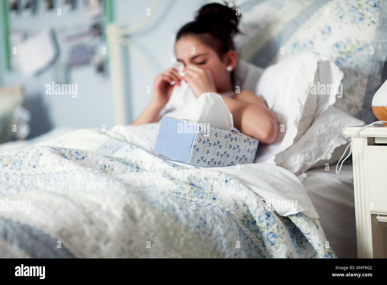 Chica en la cama sonarse la nariz en el pañuelo Foto de stock