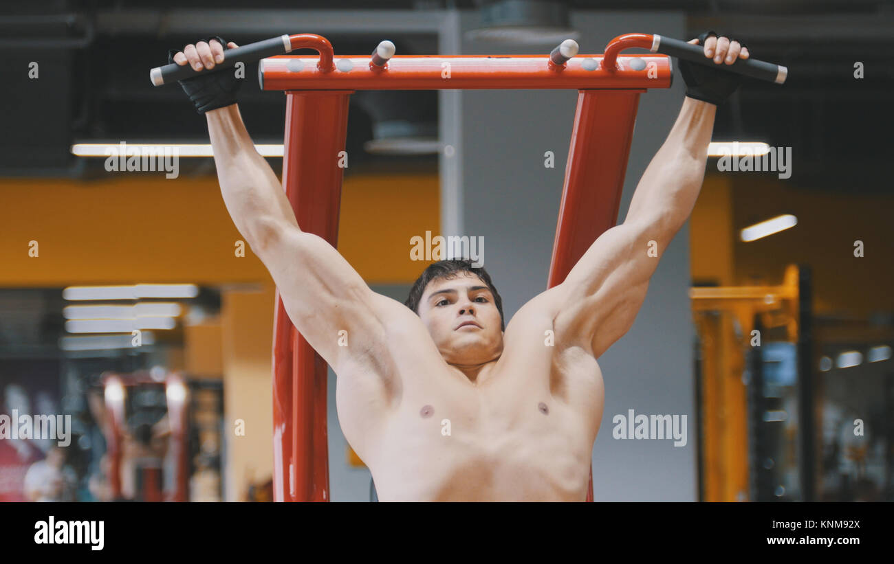 Joven atleta hombre tirando hacia arriba en un gimnasio, cerrar Foto de stock