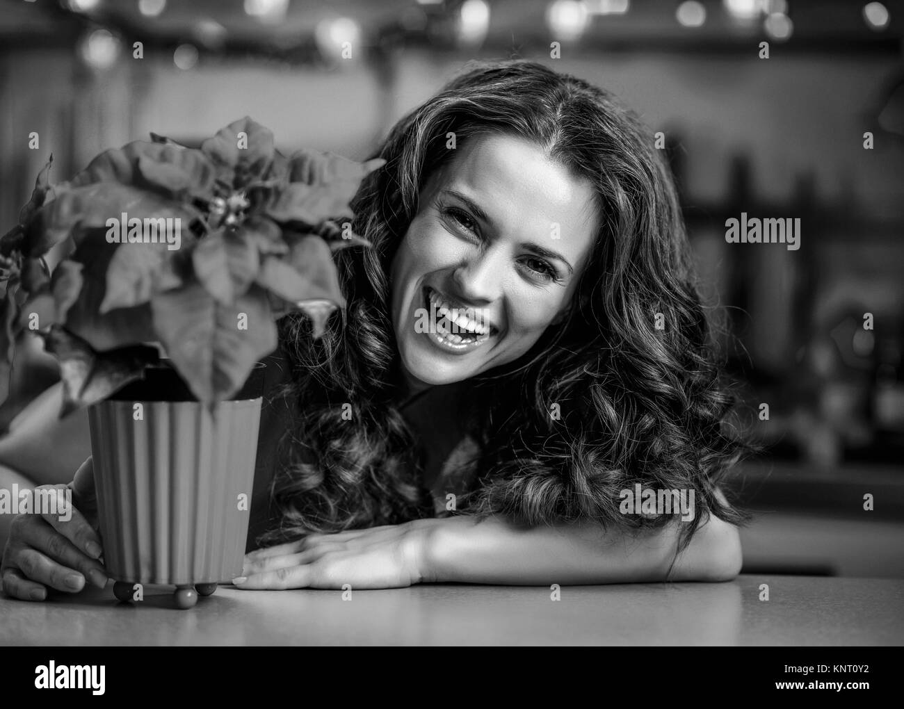 Mujer sonriente mirando desde Christmas rose en navidad decorado cocina Foto de stock